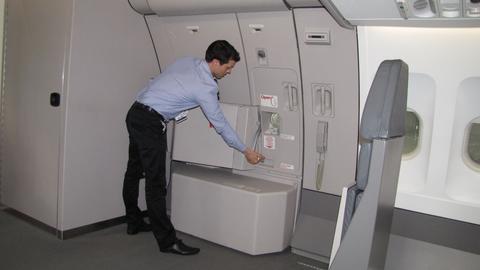 A cabin crew member in uniform closing the door of the aircraft.