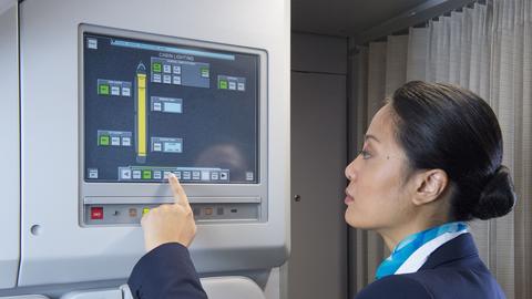 A flight attendant in uniform operating the Flight Attendant Panel (FAP) on the aircraft.