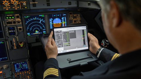 A pilot using a tablet with Flysmart+ displayed while he is in the cockpit