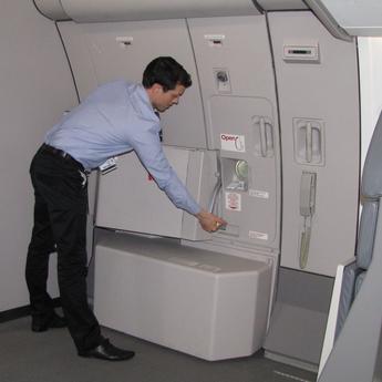 A cabin crew member in uniform closing the door of the aircraft.