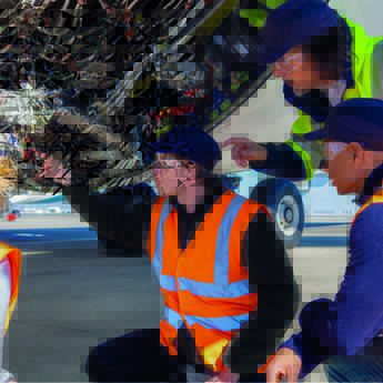 Maintenance training in action with mechanics in safety vests and goggles detecting and inspecting aircraft components