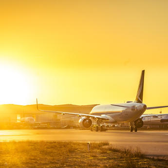 Cathay Pacific plane taxiing at sunset with a vibrant orange sky.