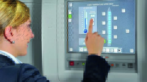 A flight attendant in uniform operating the Flight Attendant Panel (FAP) on the aircraft.