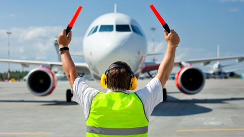 An airport staff member guiding an aircraft