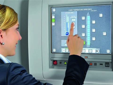 A flight attendant in uniform operating the Flight Attendant Panel (FAP) on the aircraft.