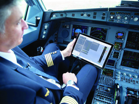 A pilot using a tablet with Flysmart+ displayed while he is in the cockpit