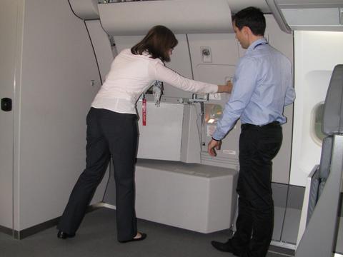 An instructor demonstrating and guiding a cabin crew trainee in closing the door of an aircraft during the training session.