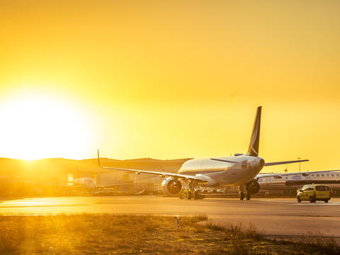 Cathay Pacific plane taxiing at sunset with a vibrant orange sky.