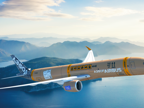 A350F in cardboard livery flying over a mountain and water landscape
