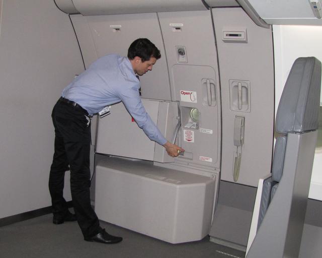 A cabin crew member in uniform closing the door of the aircraft.