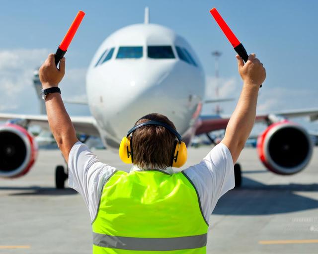 An airport staff member guiding an aircraft An airport staff member guiding an aircraft
