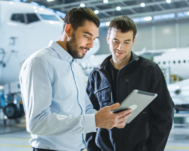 Two people looking at a tablet in an hangar Two people looking at a tablet in an hangar