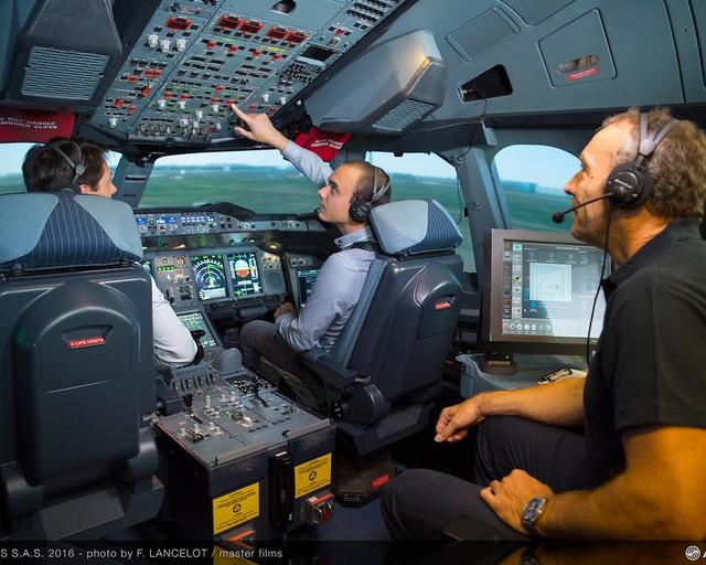 Three people in a full flight simulator during a flight training session