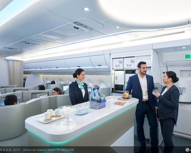 a350_xwb_mock-up_cabin_-_business_class.jpg A cabin crew member in uniform welcomes and assists passengers at the aircraft's bar