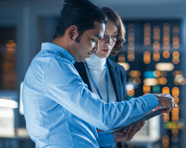 Two people working, looking at a tablet.