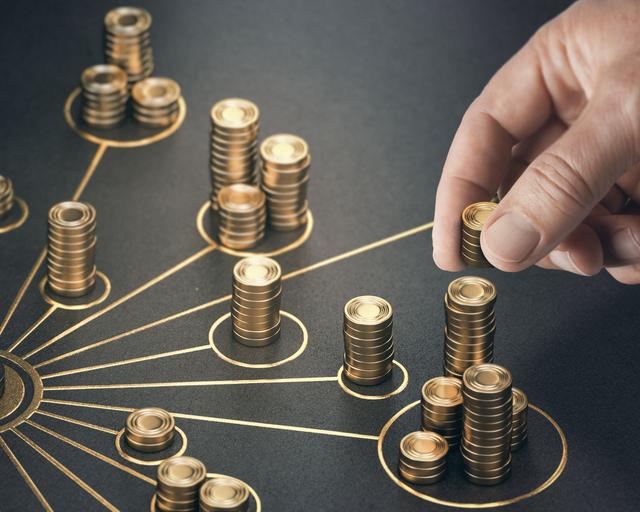 A man places gold coins on a table representing multiple income streams. A man places gold coins on a table representing multiple income streams.