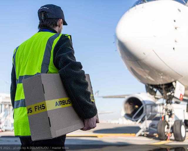 Man carrying a box towards an Airbus aircraft Man carrying a box towards an Airbus aircraft