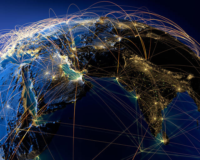 Planet Earth at night, illuminated by city lights, surrounded by a light network, representing the main air routes.