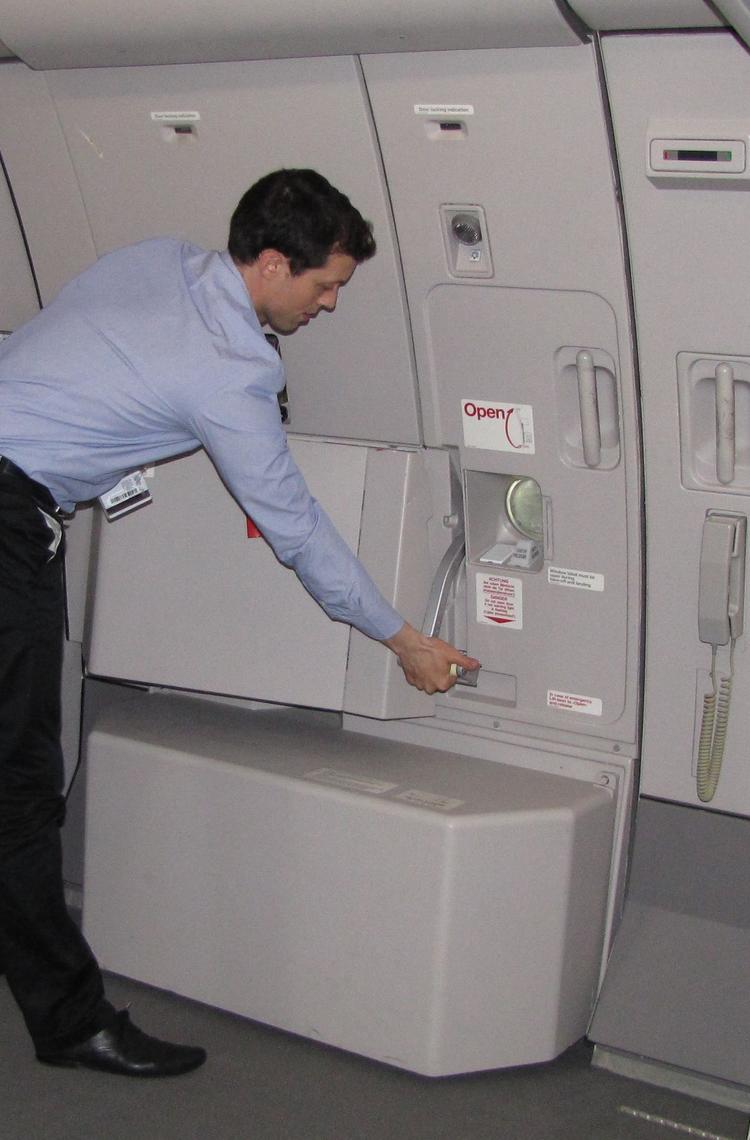 A cabin crew member in uniform closing the door of the aircraft.