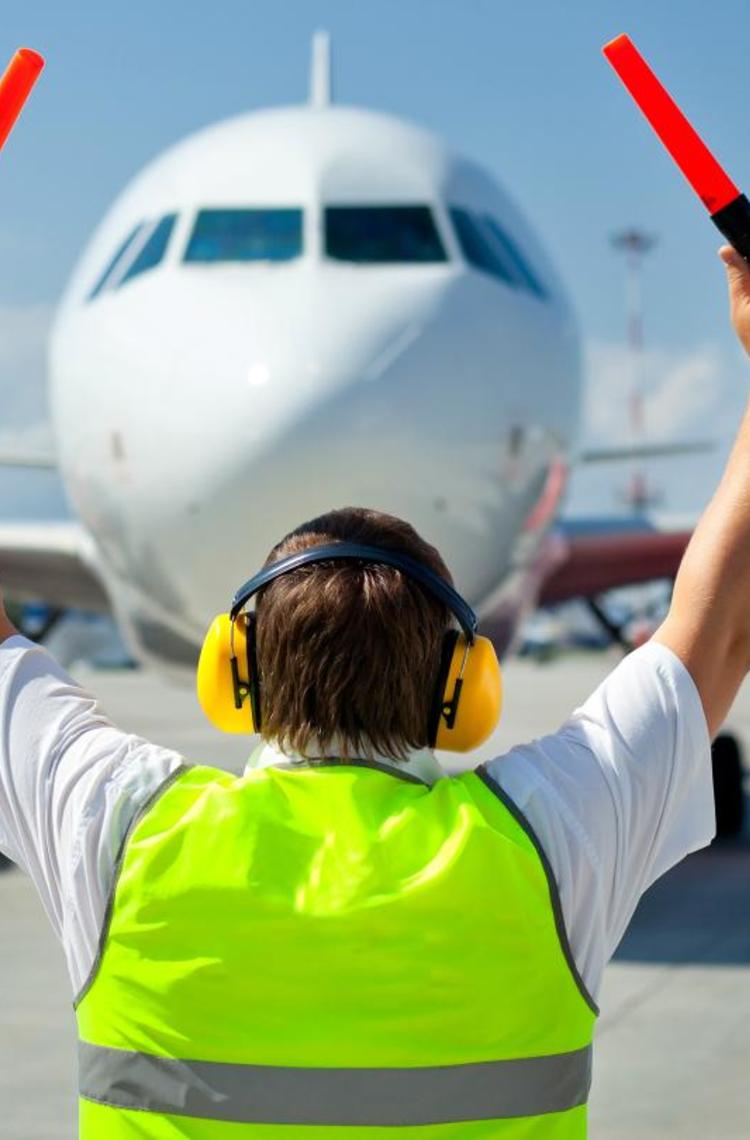 An airport staff member guiding an aircraft