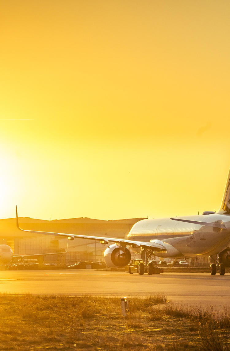 Cathay Pacific plane taxiing at sunset with a vibrant orange sky.